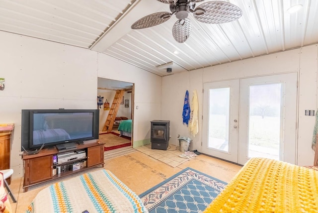 living room with a ceiling fan, a wood stove, vaulted ceiling with beams, and french doors