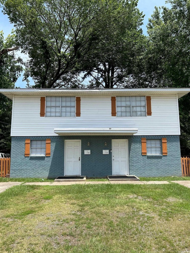 view of front of house featuring a front lawn, fence, and brick siding