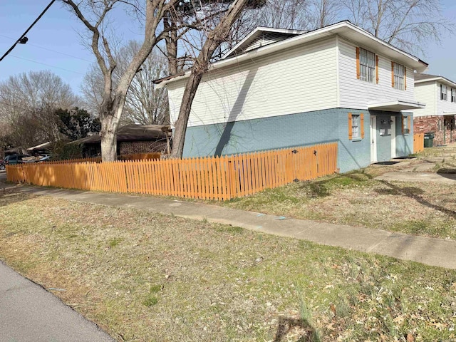 view of side of property with brick siding and fence