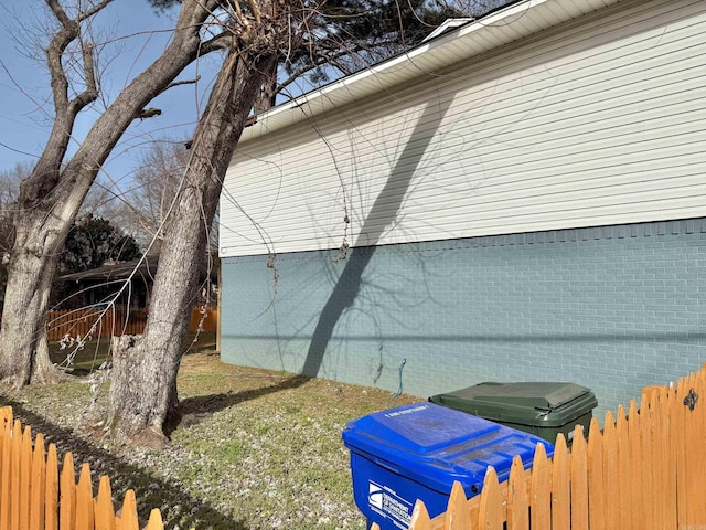 view of side of property with brick siding and fence