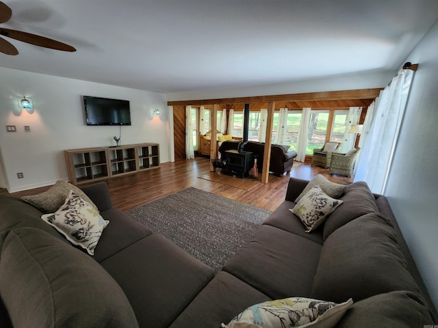 living area featuring a ceiling fan, wood finished floors, and a wood stove