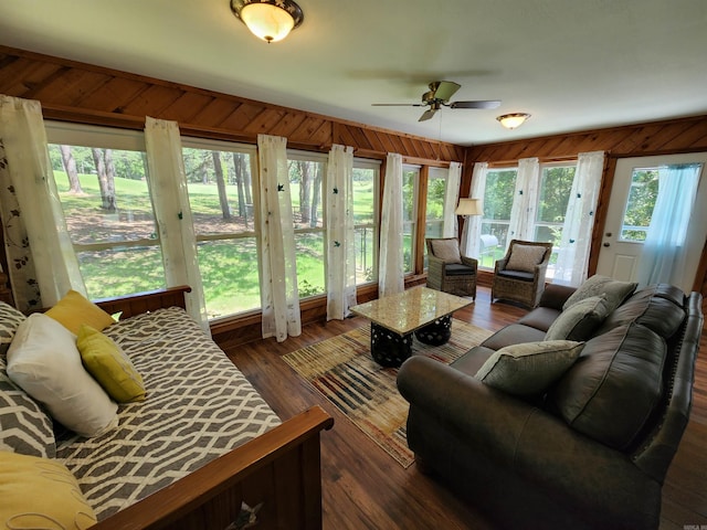 living room with plenty of natural light, dark wood-style floors, and wood walls