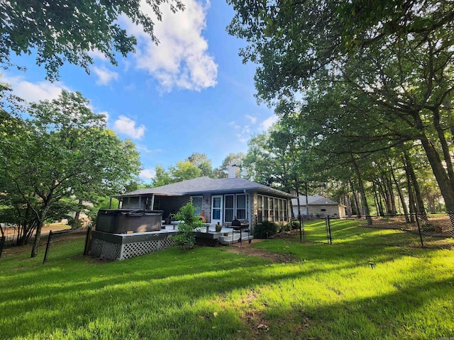 back of property featuring a lawn, a hot tub, a fenced backyard, and a gate