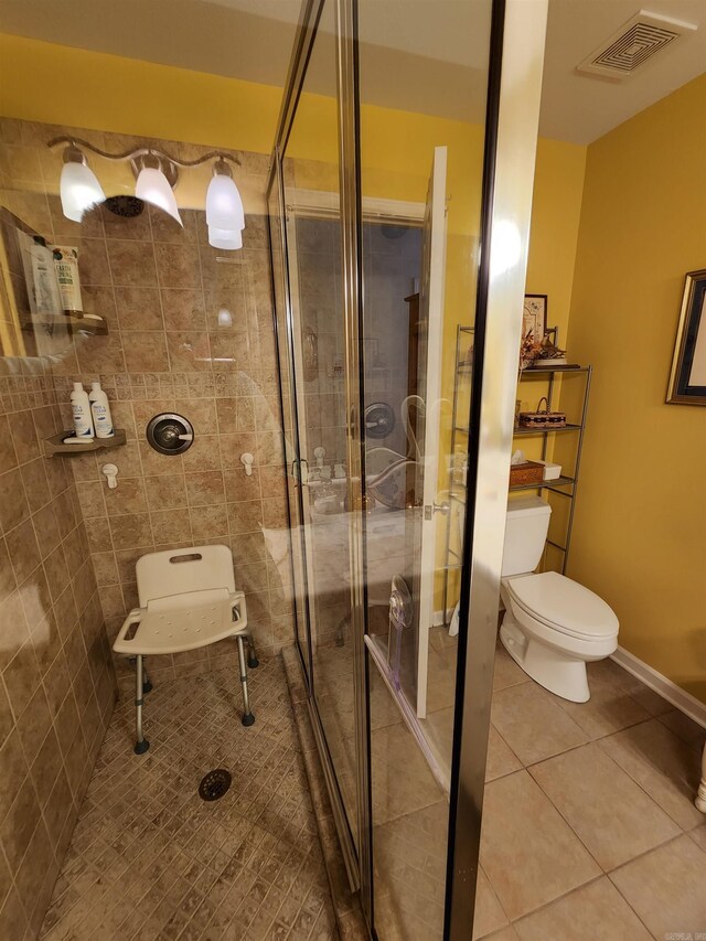 bathroom with visible vents, toilet, a shower stall, tile patterned flooring, and baseboards