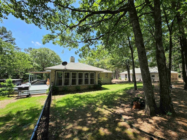 rear view of house featuring an attached carport, a lawn, brick siding, and a chimney