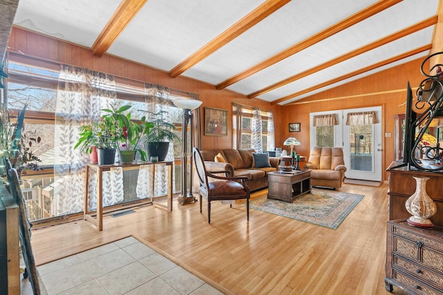 living room with lofted ceiling with beams, wood finished floors, visible vents, and wood walls