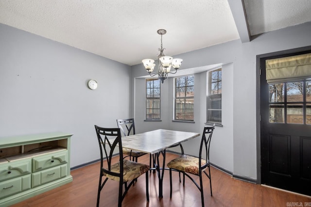 dining space with a notable chandelier, wood finished floors, baseboards, and a textured ceiling