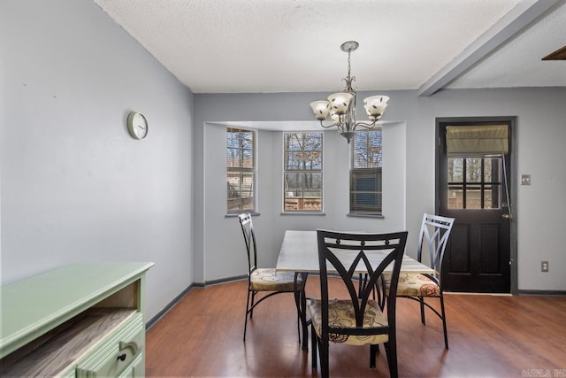 dining space featuring baseboards, a notable chandelier, wood finished floors, and a textured ceiling