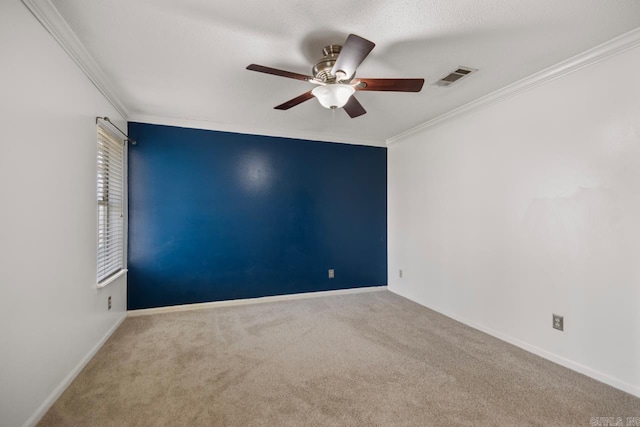 spare room with visible vents, carpet flooring, crown molding, baseboards, and ceiling fan