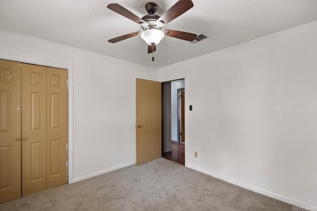 unfurnished bedroom featuring visible vents, baseboards, carpet floors, a closet, and a textured ceiling