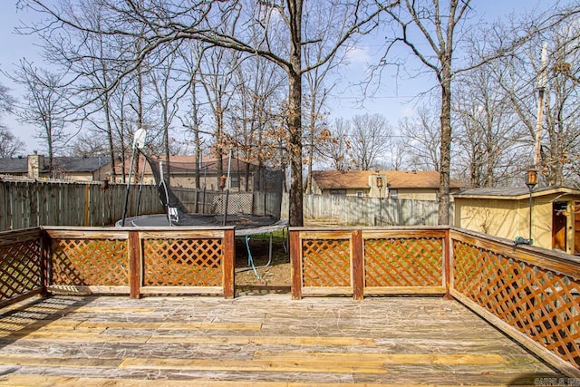 deck with a trampoline and a fenced backyard