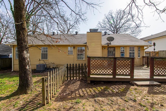 rear view of house with central air condition unit, fence, a chimney, and a wooden deck