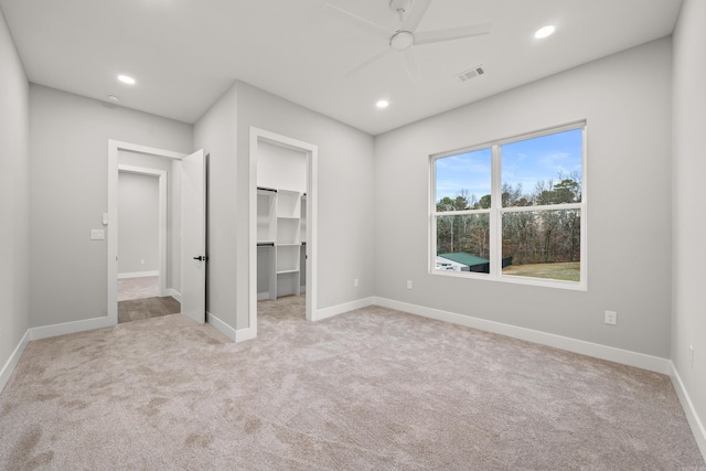 unfurnished bedroom with a spacious closet, visible vents, recessed lighting, and carpet floors