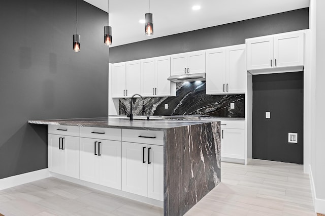 kitchen featuring under cabinet range hood, backsplash, white cabinets, and a sink