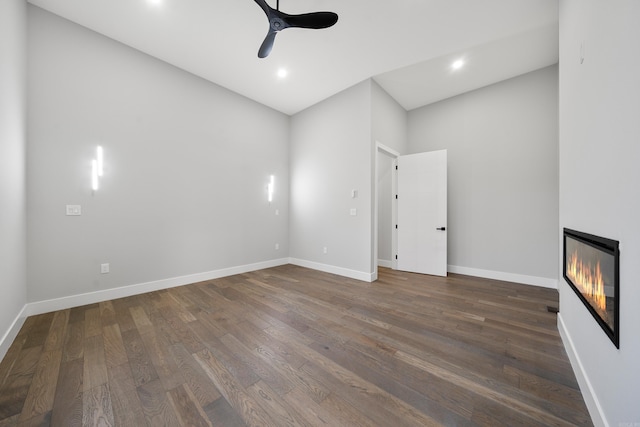 empty room featuring dark wood-style floors, baseboards, recessed lighting, ceiling fan, and a glass covered fireplace