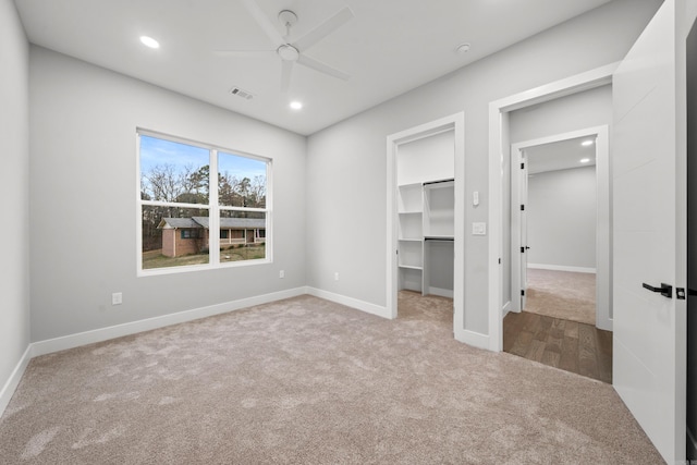 unfurnished bedroom with visible vents, recessed lighting, carpet flooring, and a walk in closet