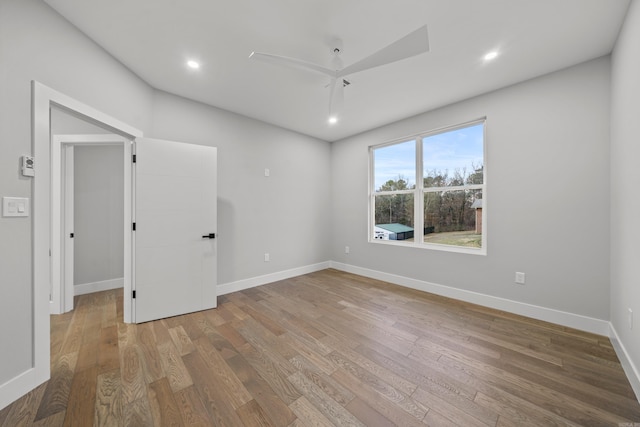 spare room featuring recessed lighting, wood finished floors, and baseboards