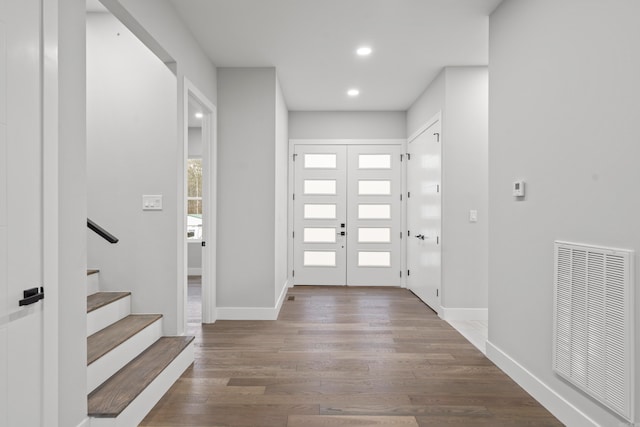 foyer with visible vents, stairway, baseboards, and wood finished floors