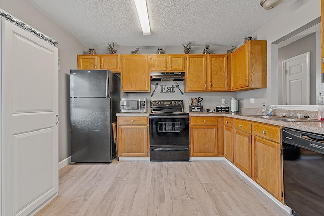 kitchen with light wood-style flooring, black appliances, light countertops, under cabinet range hood, and a textured ceiling