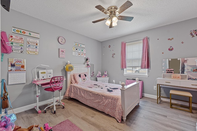 bedroom featuring light wood-type flooring, baseboards, a textured ceiling, and a ceiling fan