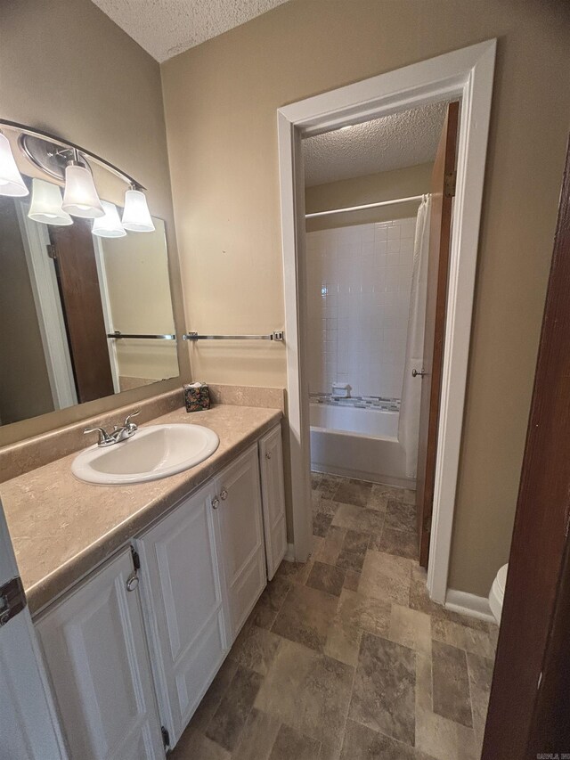 bathroom featuring toilet, a textured ceiling, vanity, and baseboards