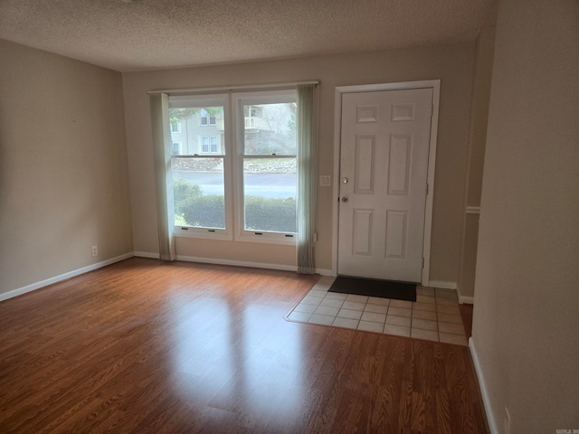 doorway featuring wood finished floors, baseboards, and a textured ceiling