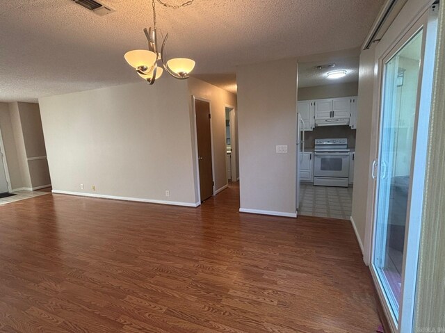 interior space featuring visible vents, dark wood-type flooring, baseboards, a notable chandelier, and a textured ceiling