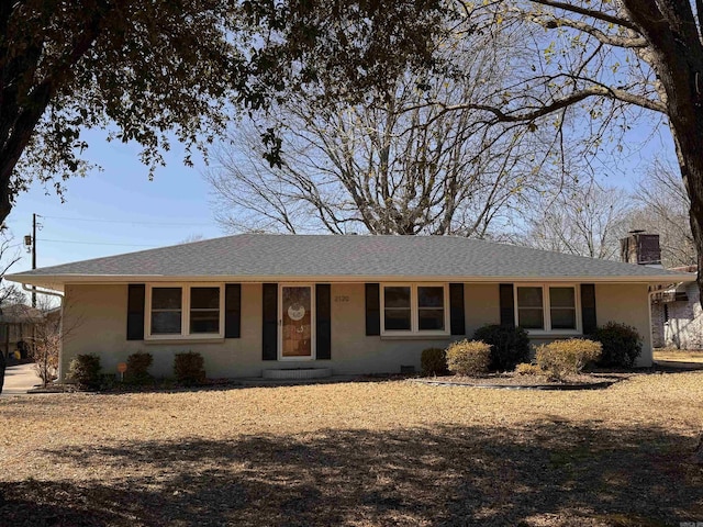 ranch-style home featuring stucco siding, roof with shingles, and a chimney