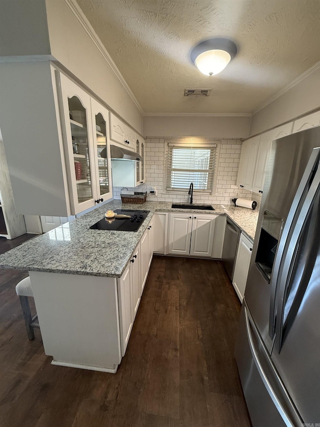 kitchen with dark wood-style floors, visible vents, a sink, ornamental molding, and stainless steel appliances