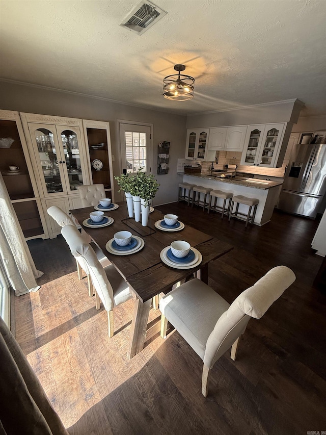 dining space with visible vents, a textured ceiling, and dark wood-style flooring