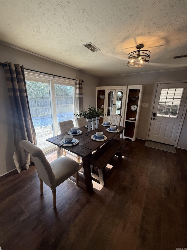 dining area featuring visible vents, a textured ceiling, and wood finished floors