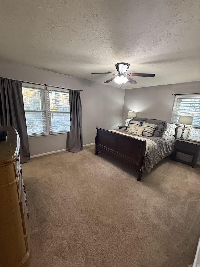 unfurnished bedroom with a textured ceiling, multiple windows, light colored carpet, and ceiling fan