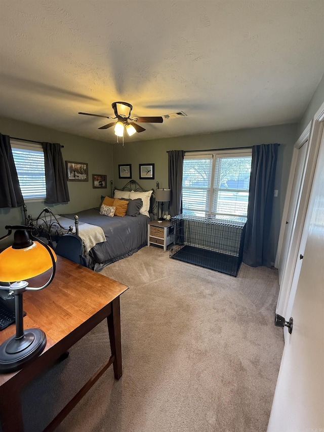 carpeted bedroom with visible vents, a textured ceiling, and ceiling fan