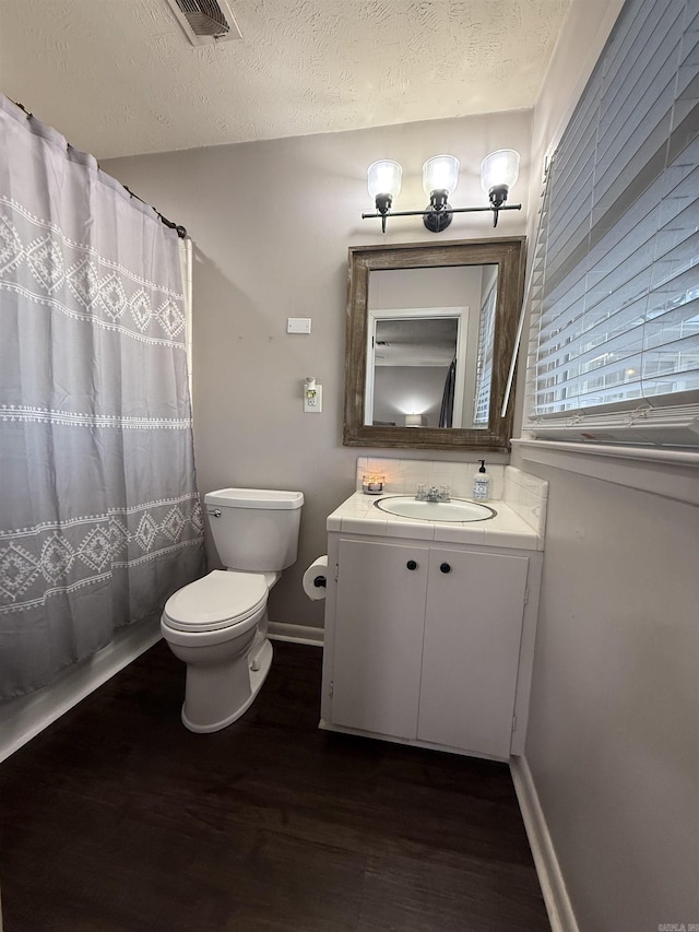 bathroom with visible vents, toilet, vanity, wood finished floors, and a textured ceiling