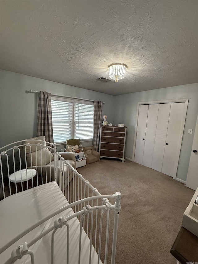 bedroom featuring a closet, visible vents, a textured ceiling, and carpet