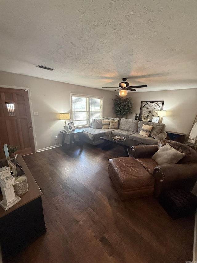 living area featuring visible vents, a textured ceiling, wood finished floors, baseboards, and ceiling fan