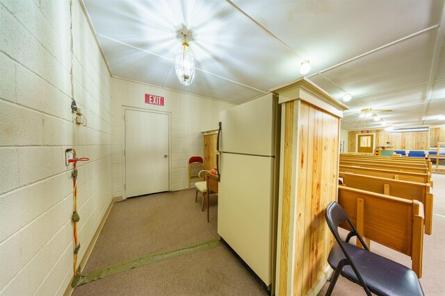 hall featuring carpet flooring and concrete block wall