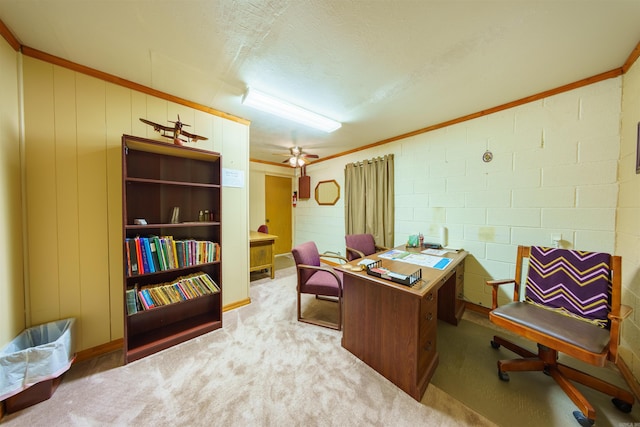 carpeted home office with crown molding, concrete block wall, and a ceiling fan