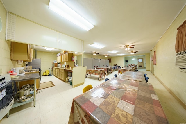 kitchen with open floor plan, concrete block wall, and a ceiling fan