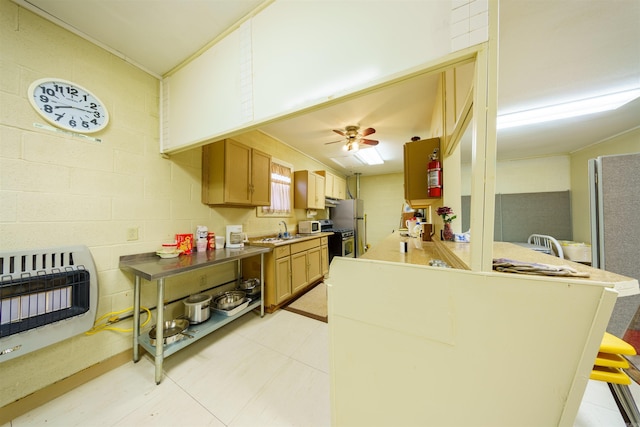 kitchen featuring heating unit, a ceiling fan, a peninsula, a sink, and stainless steel gas range oven