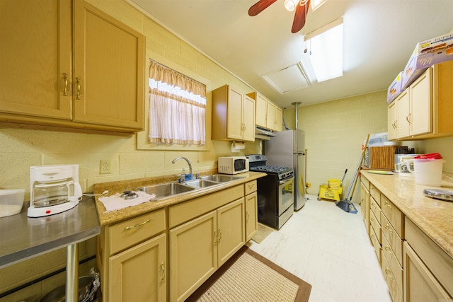 kitchen with a ceiling fan, a sink, light countertops, under cabinet range hood, and appliances with stainless steel finishes