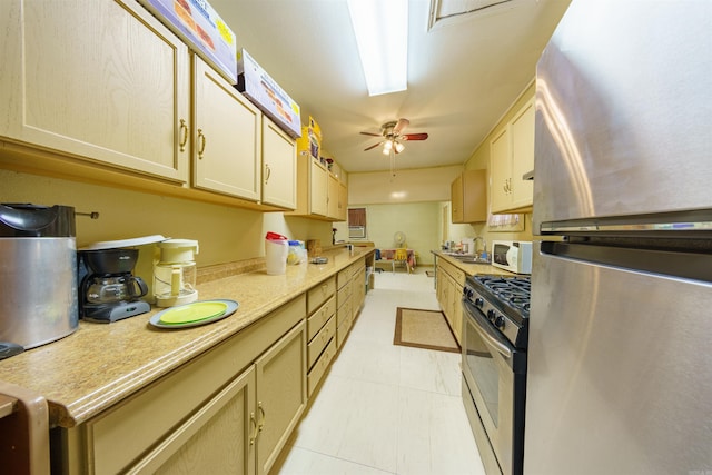 kitchen with light tile patterned flooring, stainless steel appliances, light countertops, and a ceiling fan