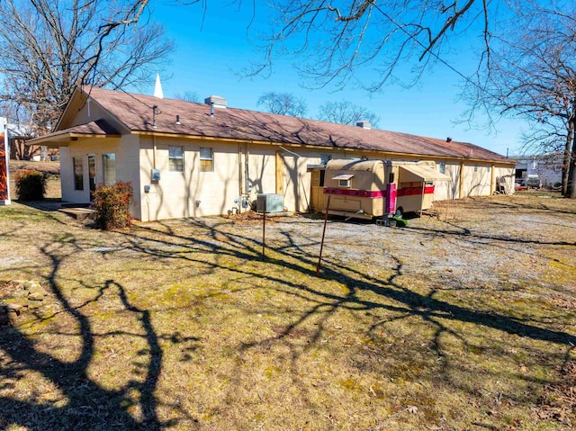 back of house featuring central air condition unit, a lawn, and a chimney