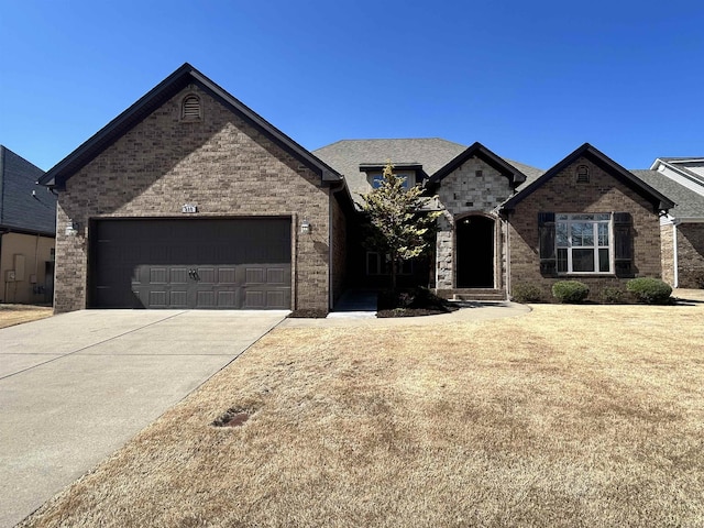 french provincial home featuring brick siding, an attached garage, and driveway