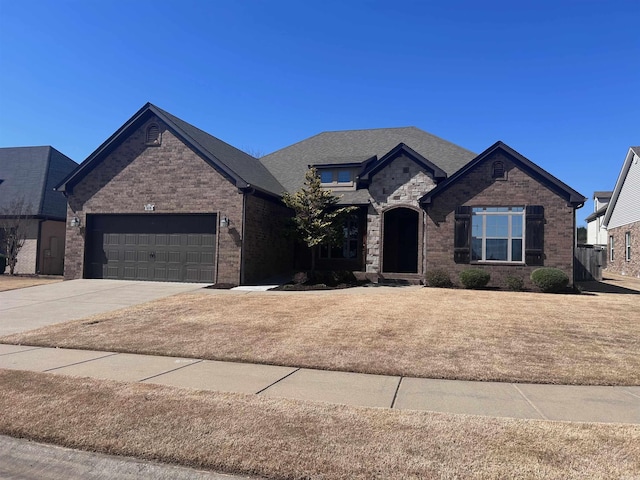 french provincial home featuring concrete driveway, an attached garage, and brick siding