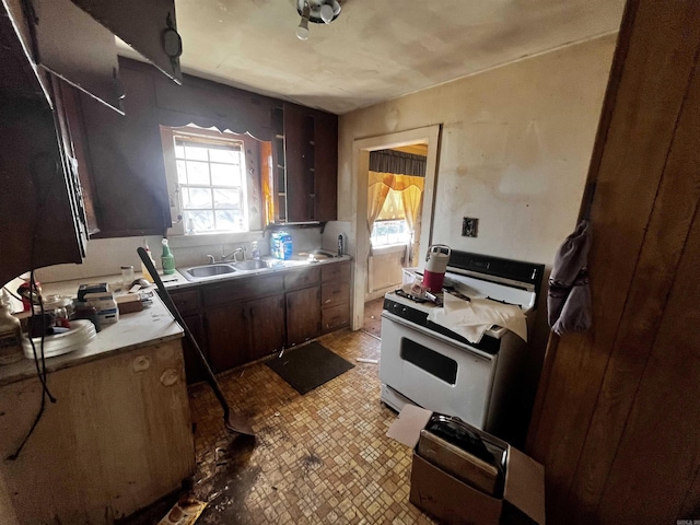 kitchen with light countertops, white gas range oven, and a sink