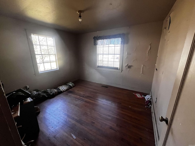 spare room featuring hardwood / wood-style flooring, a healthy amount of sunlight, and visible vents