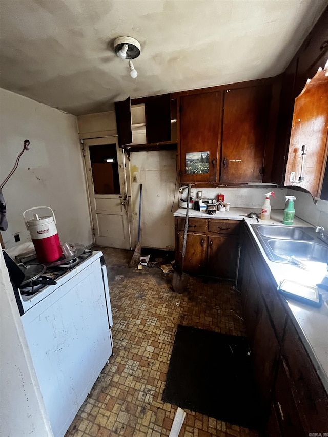 kitchen with a sink, white range with gas cooktop, and light countertops