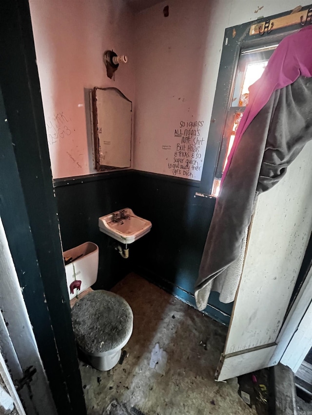 bathroom featuring a sink, toilet, and unfinished concrete floors