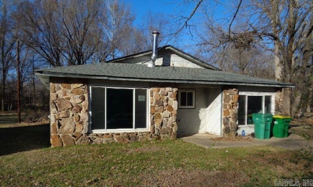 rear view of property with stone siding and a lawn